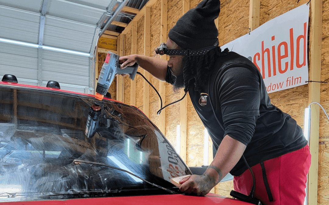 Expert technician at YBNT Kustomz meticulously heat-shrinks Geoshield ceramic window tint on a car windshield, demonstrating precision in automotive tinting services for enhanced UV protection and visual perfection in Hagerstown, MD.